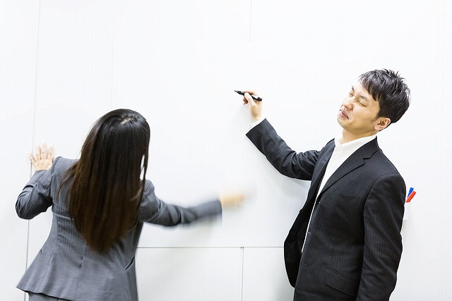 ホワイトボードを消す女性